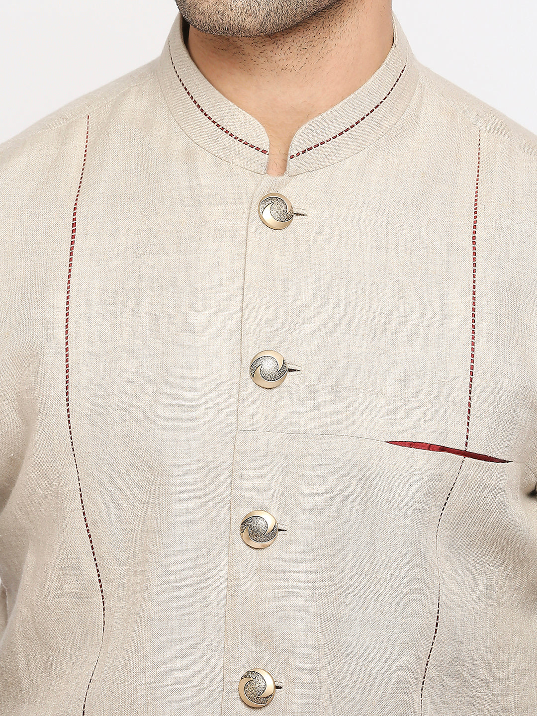 Close-up of a man wearing a light beige linen kurta with a mandarin collar, three decorative buttons, and red contrast stitching.