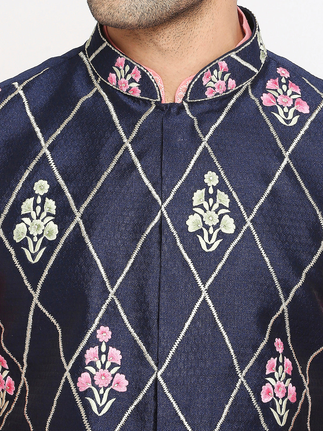 Close-up of a navy blue embroidered kurta or sherwani with a mandarin collar, featuring a silver geometric diamond pattern and pink floral motifs.