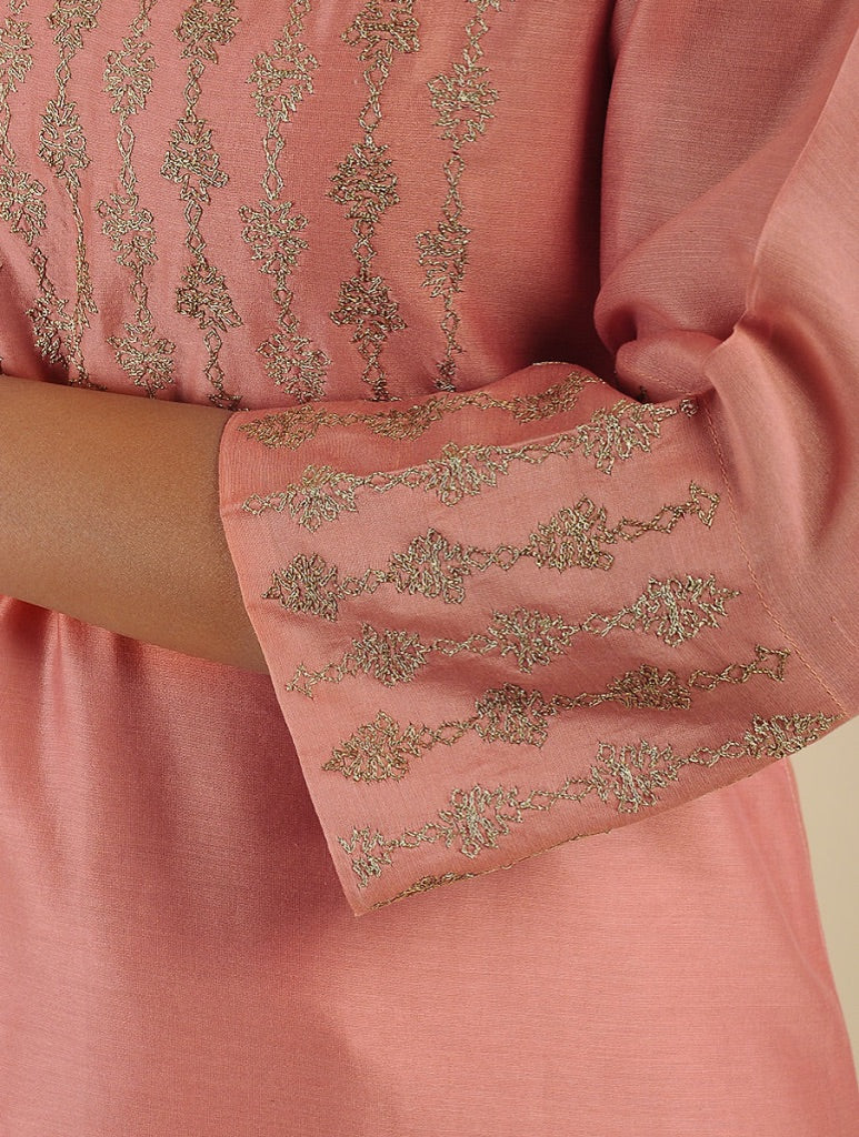 Close-up of a dusty pink kurta with metallic gold embroidery on the sleeve and bodice, worn by a model.