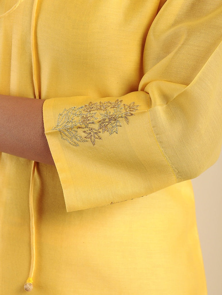 Close-up of a yellow kurta sleeve with silver floral embroidery and a drawstring detail, worn by a model.